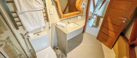 A bathroom with a toilet, sink, mirror, towel rack, and shower area.