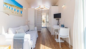 Ein kleines Zimmer mit Bett, Schreibtisch, Stuhl, Fernseher und einem Bild an der Wand.