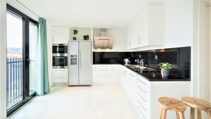 Eine moderne Küche mit großem Fenster, einem Kühlschrank, einem Backofen und einer Spüle.