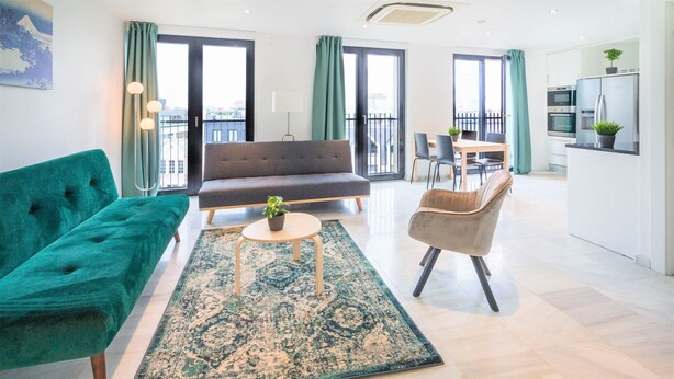 Ein modernes Wohnzimmer mit einer Couch, einem Sessel und einem kleinen Tisch mit einer Pflanze.