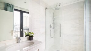 Ein modernes Badezimmer mit einer Duschkabine aus Glas, einem weißen Waschbecken und einer Toilette.
