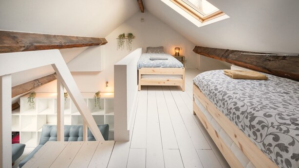 A loft bedroom with a skylight, a bed, a desk, and a built-in bench. - 3-bedroom apartment in National Residence (Belgium)
