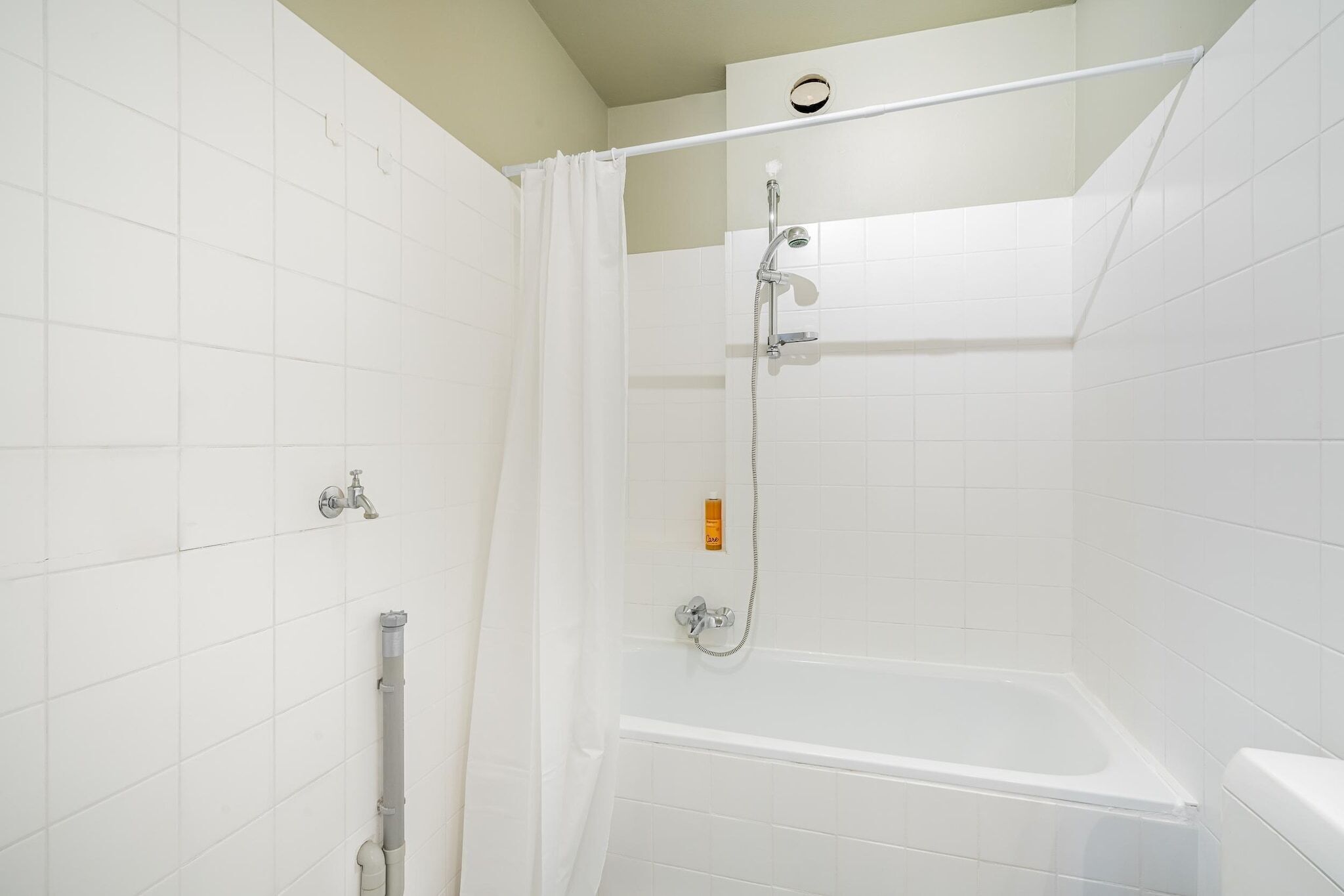 A shower with a glass door, a handheld showerhead, and a wall-mounted faucet.