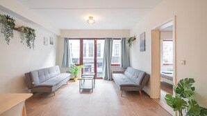 Uma sala de estar moderna com dois sofás cinzas, uma mesa de centro e um vaso de planta.