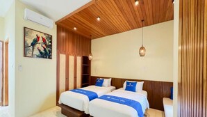 Une chambre d’hôtel avec deux lits, un plafond en bois et un tableau représentant des perroquets.