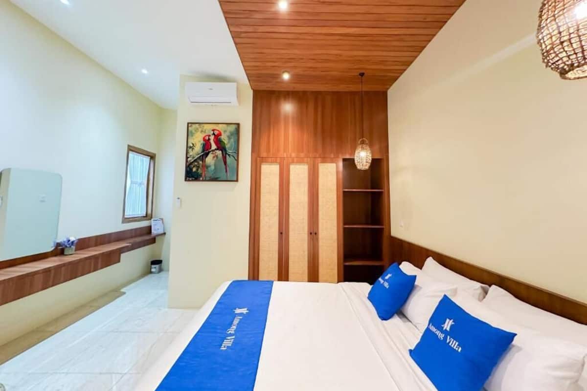 Ein Hotelzimmer mit einem Bett, einer Holzbalkendecke, einem an der Wand montierten Fernseher und einem Gemälde.