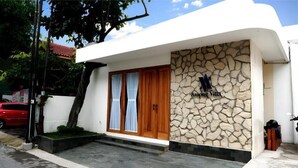 Un bâtiment moderne avec une façade en pierre, une porte en bois et une enseigne indiquant « Amone Villa ».
