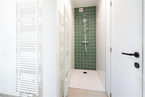 A bathroom with a shower, a white radiator, and a green tiled wall. - Saint Pauls Deluxe Apartment (Antwerp)