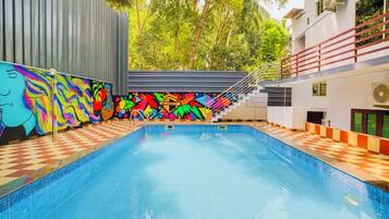 A swimming pool with colorful murals on the walls, a checkered floor, and a staircase leading to an upper level.