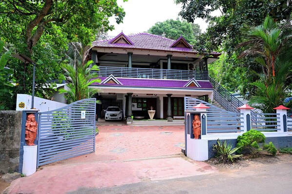 A two-story house with a purple roof, a gated entrance, and a staircase leading to the upper floor. - Harbour villa (Thiruvananthapuram)