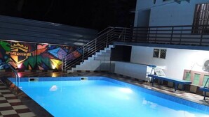A swimming pool with a checkered floor, stairs, and a colorful mural in the background.