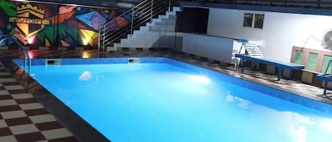 A swimming pool with a checkered floor, stairs, and a colorful mural in the background.