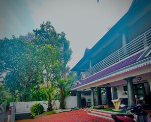A building with a traditional architectural style, a covered entrance, and a red-tiled pathway leading to the main entrance.
