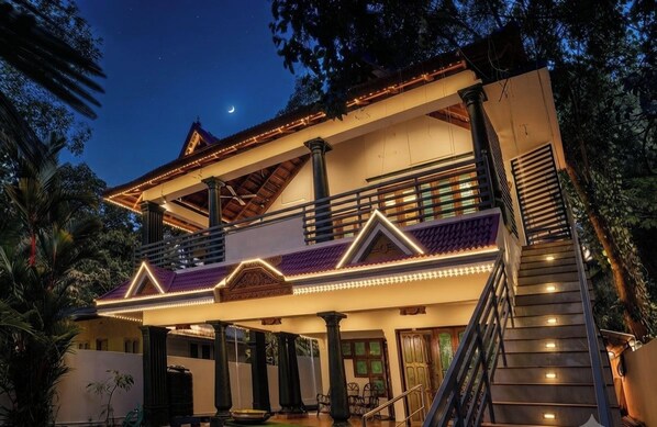 A two-story building with a balcony, stairs, and a view of the night sky.