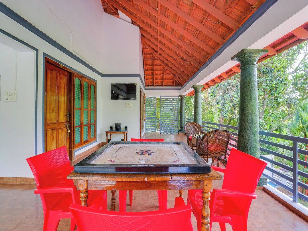 A room with a wooden ceiling, a table with chairs, a television, and a view of greenery outside.
