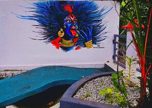 A mural of a deity with a blue and red face, a blue and red headdress, and a red and gold outfit. - Harbour villa (Thiruvananthapuram)