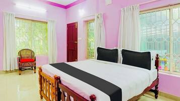 A bedroom with a bed, a chair, and a window with curtains.