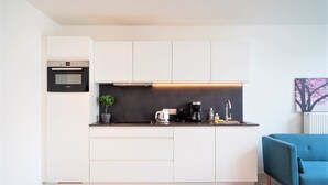 Une cuisine moderne avec des meubles blancs, un four Bosch, une machine à café et un évier.