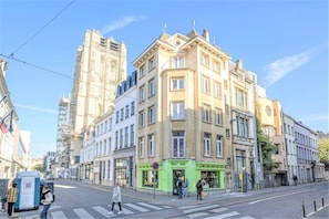 Een meerlaags gebouw met een groene gevel met daarop de tekst 'DELI BOX', een zebrapad en een voetgangersoversteekplaats.