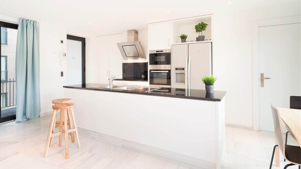 A modern kitchen with a central island, stainless steel appliances, and wooden stools. - 2-bedroom apartment in Central Antwerp (Antwerp Center)