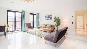 A modern living room with a sofa, armchair, dining table, and chairs. - 2-bedroom apartment in Central Antwerp (Antwerp Center)