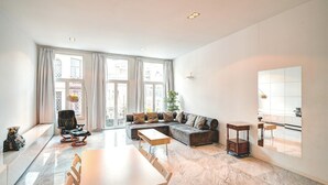 A spacious living area with a sofa, a dining table, and a large window.