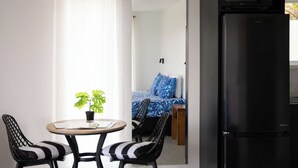 A compact room with a dining table, two chairs, a black refrigerator, and a bed with blue bedding. - Modern Style Villas 5 Min Walk to the Best beach on the Island
Unlimited WIFI In (Rarotonga)