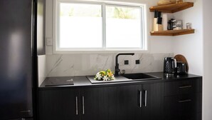 A modern kitchen with a black countertop, a double sink, and a window above the sink. - Modern Style Villas 5 Min Walk to the Best beach on the Island
Unlimited WIFI In (Rarotonga)
