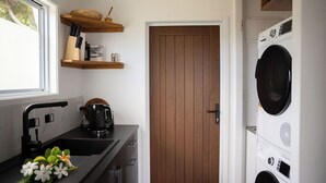 A compact kitchen with a sink, a kettle, and wooden shelves above it. - Modern Style Villas 5 Min Walk to the Best beach on the Island
Unlimited WIFI In (Rarotonga)