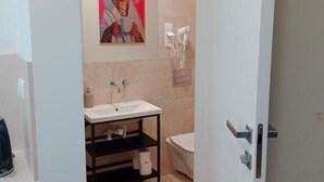 A modern bathroom with a white sink, a toilet, and a shower area.