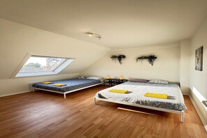 Ein Schlafzimmer mit zwei Betten, einem Dachfenster, einem kleinen Tisch und Wanddekorationen.