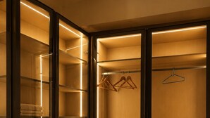 A walk-in closet with multiple shelves and hanging space, illuminated by under-cabinet lighting.