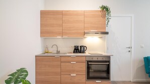 Een moderne keuken met houten kastjes, een inbouwoven, een koffiezetapparaat en een plant op het aanrecht.
