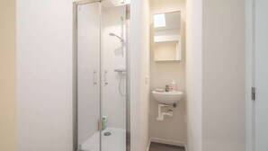 Een badkamer met een douchecabine van glas, een wastafel met een spiegel erboven en een toilet.
