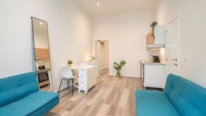 Een compacte leefruimte met een kitchenette, een eethoek en twee blauwe banken.