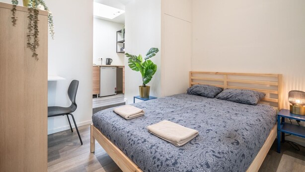 A bedroom with a bed, a desk, a chair, a potted plant, and a bedside table. - Romantic apartment in Antwerp Centre (Antwerp)