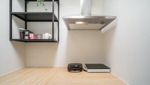 A kitchen with a wooden countertop, a black shelf with kitchen items, a stainless steel range hood, and a small black appliance. - Romantic apartment in Antwerp Centre (Antwerp)