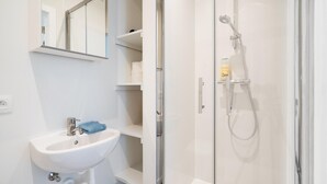 A modern bathroom with a glass-enclosed shower, a white sink, and a mirror.