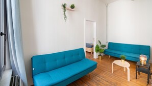 Een woonkamer met twee blauwe banken, een kleine ronde tafel en een potplant.