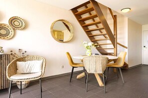 A modern interior with a spiral staircase, wicker furniture, and a dining area. - Beautiful modern furnished apartment (Callantsoog)