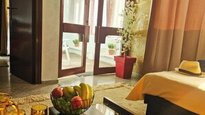 A hotel room with a bed, a dining table with fruit, a plant, and a view through the door. - Le Vintage · Tanger Corniche - Sea view, private parking & terrace (Tangier)