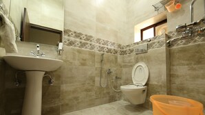 A bathroom with a sink, toilet, shower, and a large orange bucket. - Hotel Rawat Near Railway Station, Jaipur (Jaipur)