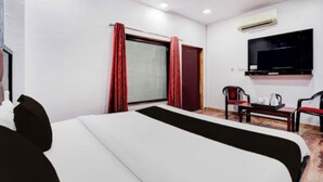 A hotel room with a bed, a TV, a desk with a chair, and a window with curtains. - Hotel Rawat Near Railway Station, Jaipur (Jaipur)
