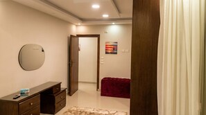 Une chambre à coucher avec un lit, une commode, un miroir, un tableau et une porte.
