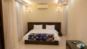 Ein Hotelzimmer mit einem Bett, einer Klimaanlage, einem Nachttisch und einer Fernbedienung.