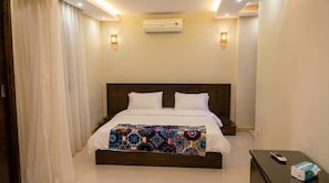 Une chambre d’hôtel équipée d’un lit, d’un climatiseur, d’une table de chevet et d’une télécommande.