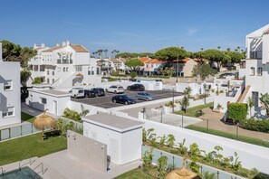 Un quartier résidentiel avec des bâtiments blancs, un parking et une piscine.