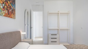 A bedroom with a bed, bedside table, lamp, and a wardrobe.