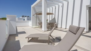 A rooftop terrace with a lounge chair, a table with chairs, and a pergola with umbrellas. - Apartment 'Los Drogos, Building B, Penthouse B' with shared pool, garden & Wi-Fi (Chiclana de la Frontera)