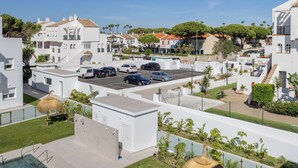 Uma área residencial com edifícios brancos, um estacionamento e uma piscina.
